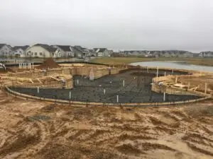 A large commercial gunite swimming pool under construction, showcasing an intricate rebar curtain and plumbing lines before the concrete pour in a residential development.
